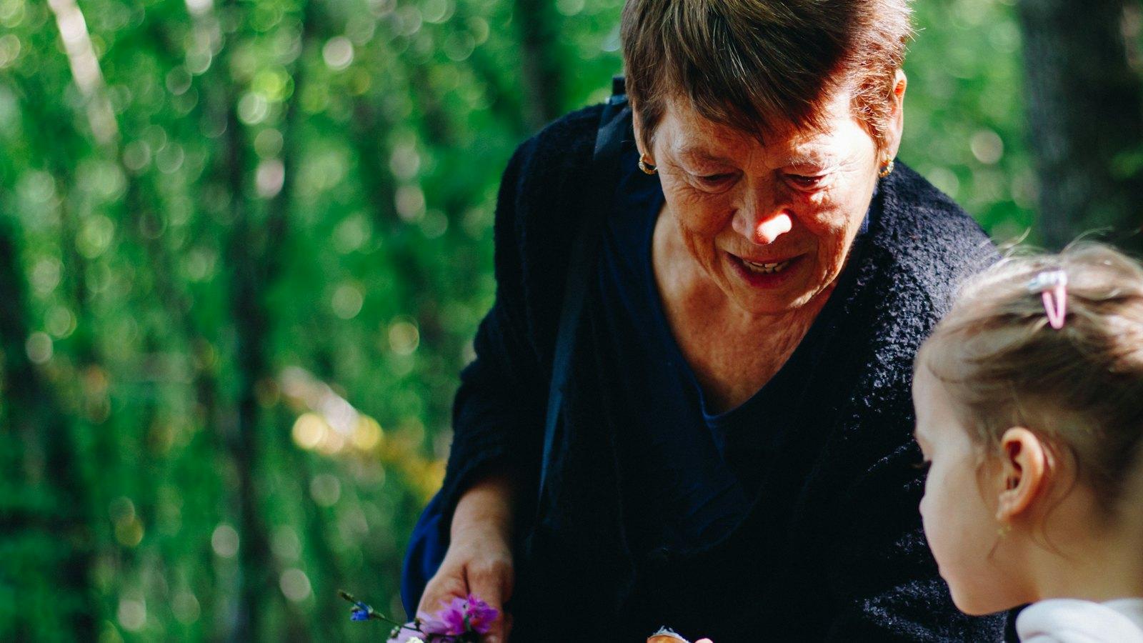 Grandmother showing flowers to her granddaughter in a garden