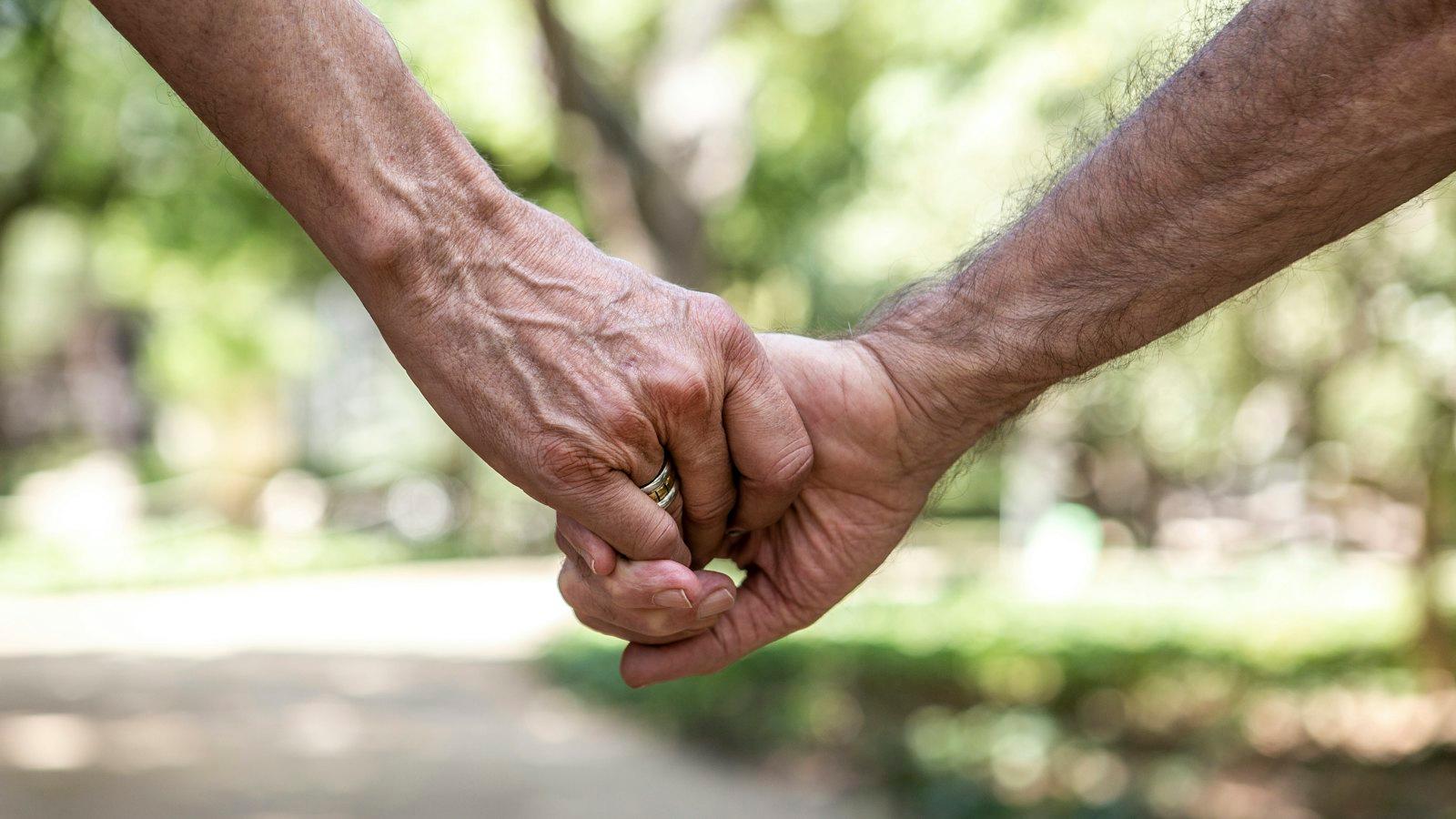 Two older people holding hands on a walk