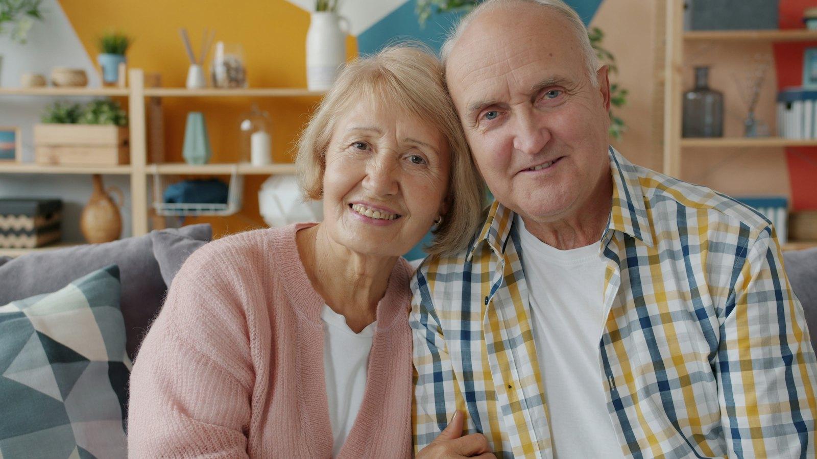 Smiling older couple sitting close together on their sofa