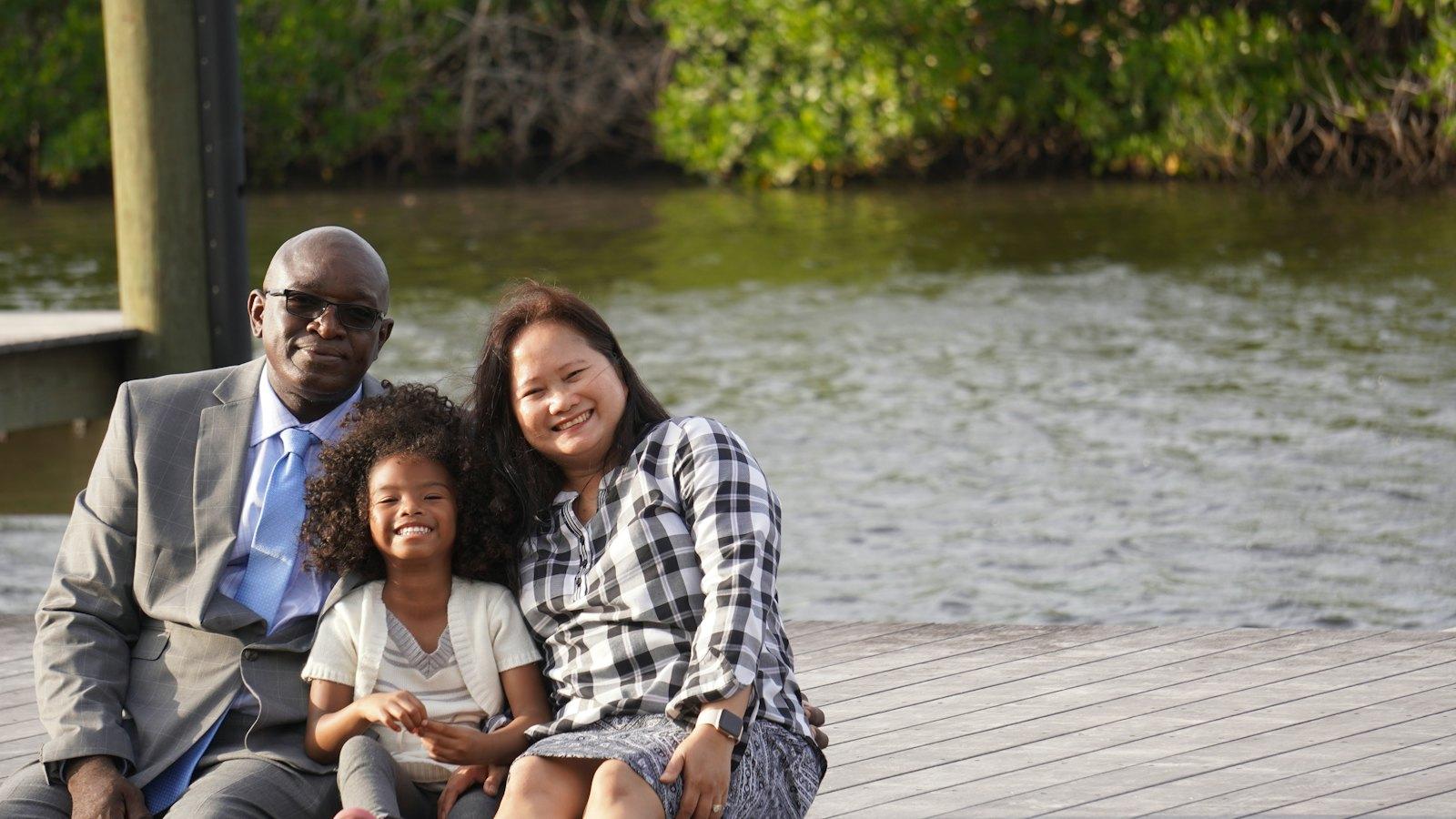Grandparents and grandchild sitting together on a dock