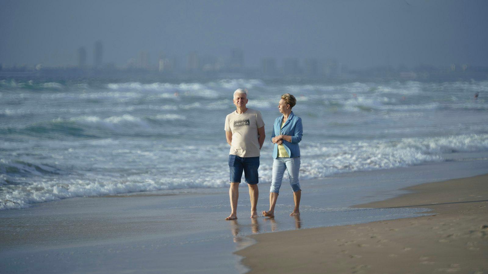 Couple in their sixties walking along the shoreline