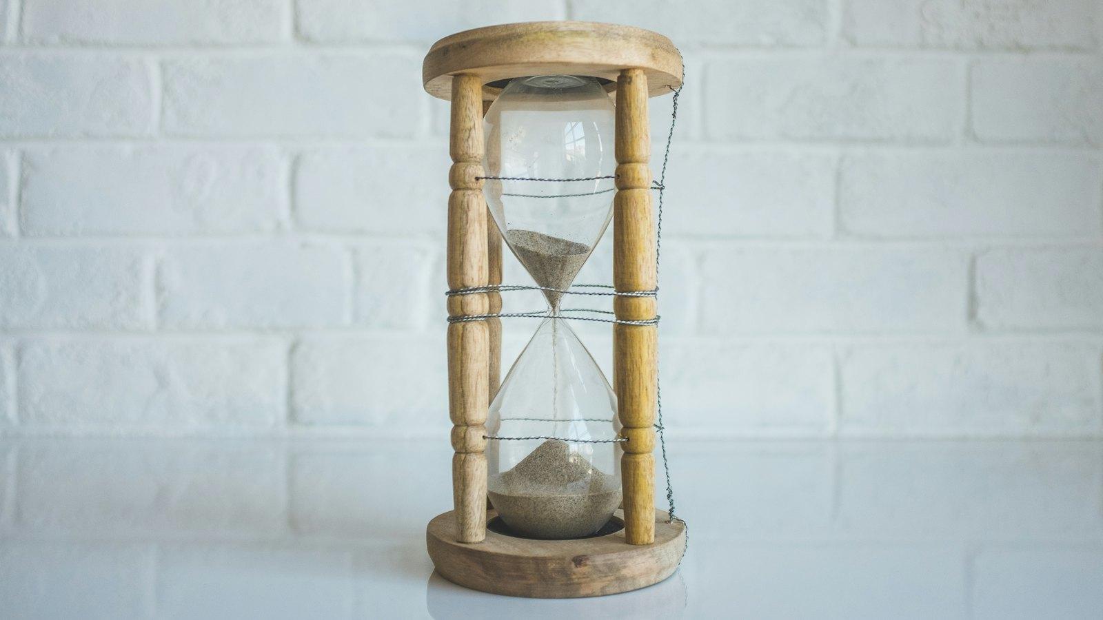 Wooden hourglass with sand running through it