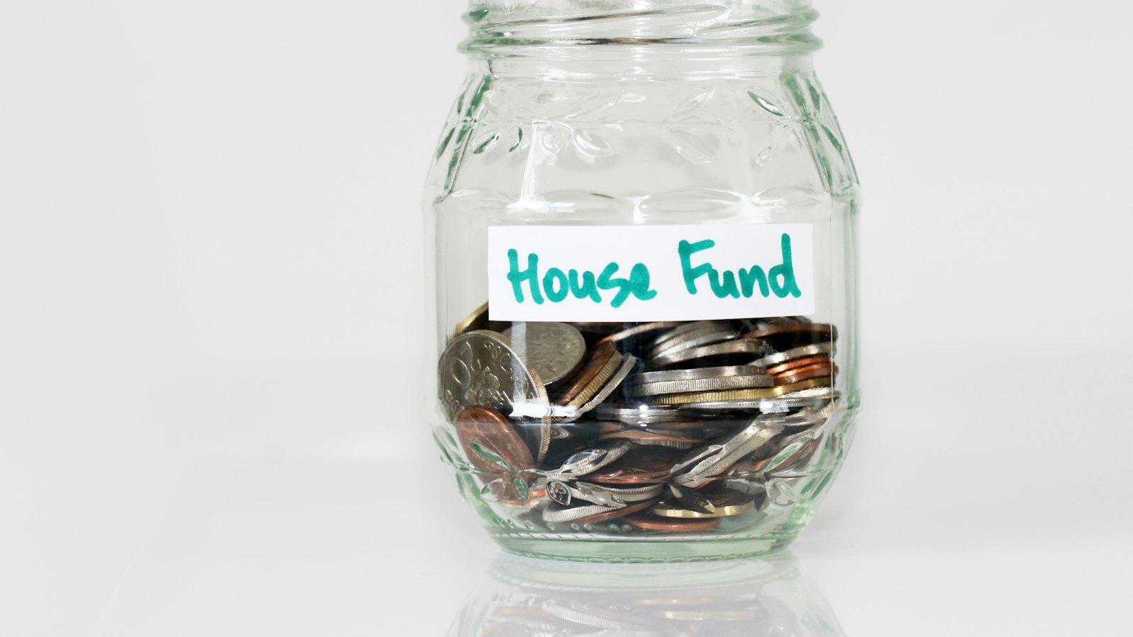 Glass jar of coins labeled house fund