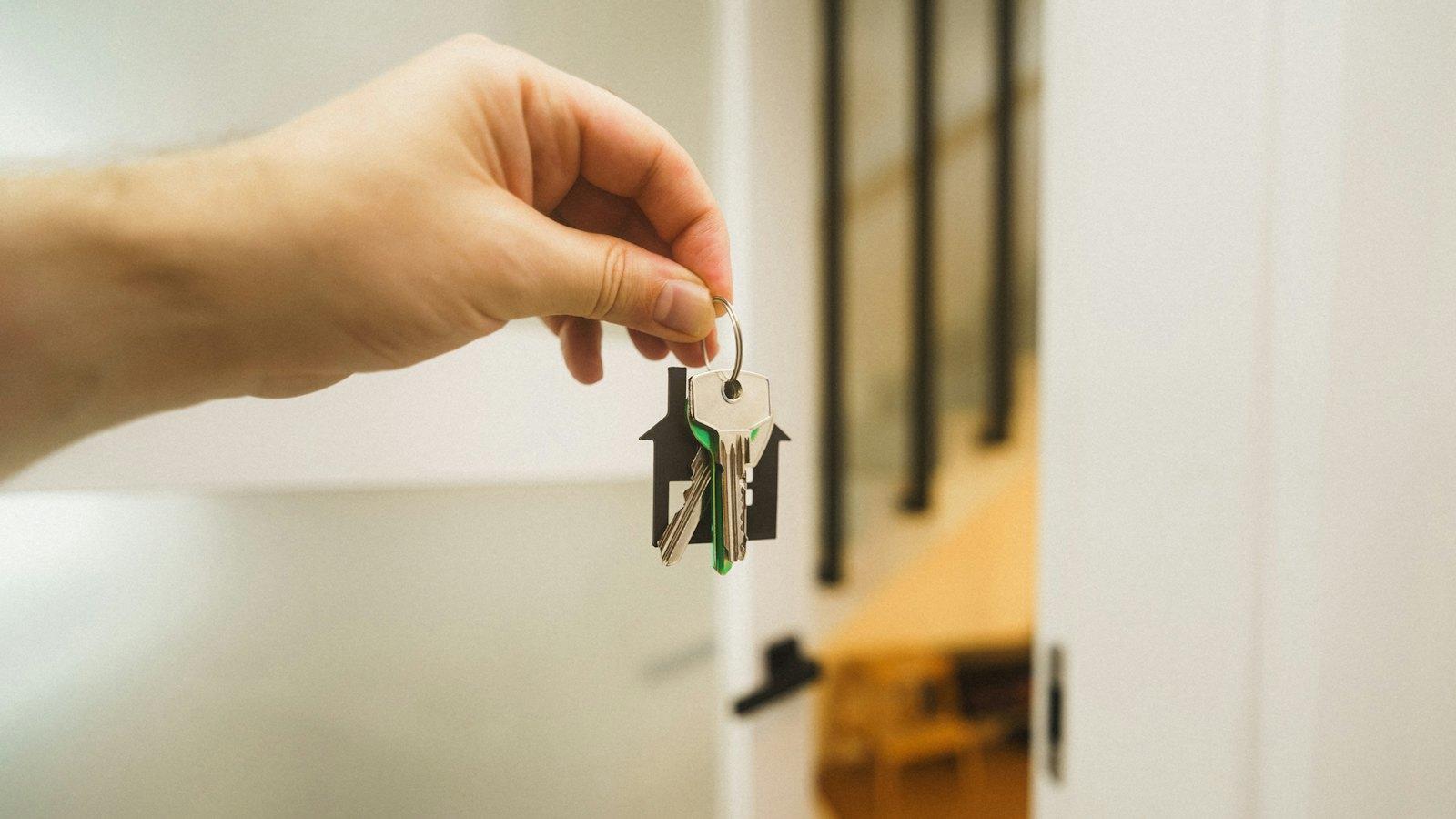 Hand holding house keys in a doorway